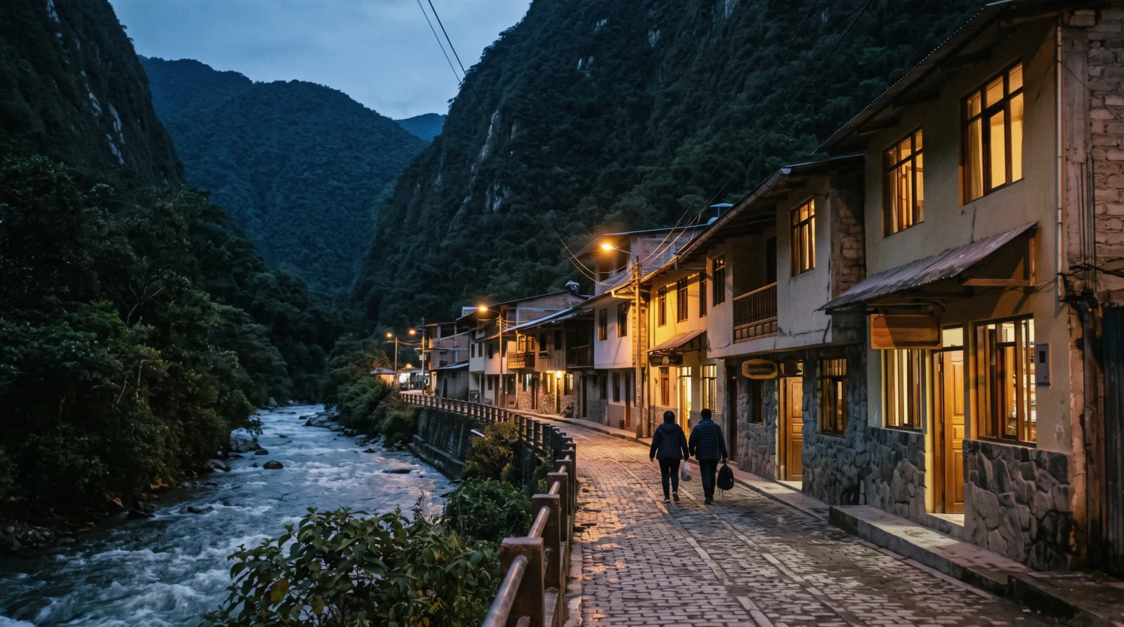 Aguas Calientes after dark, with buildings along the river and the canyon walls above the town